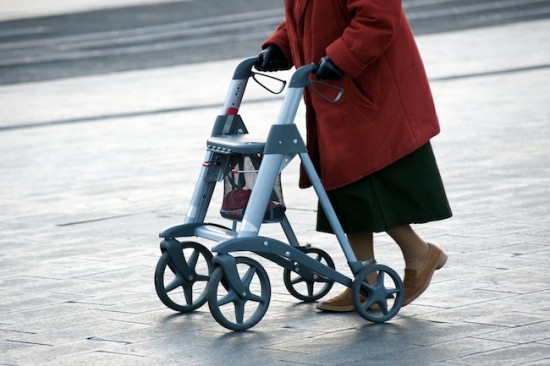 An elderly woman walking on the street with her walking frame
